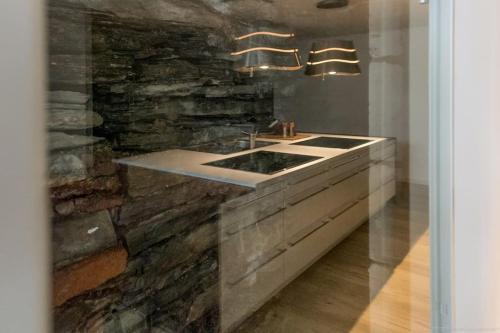 a kitchen with a sink and a stone wall at Stadthaus Monschau Aqua&Blue (14 Gäste) in Monschau