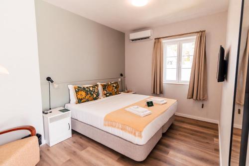 a bedroom with a large bed and a window at Dear Faro - Guest House in Faro