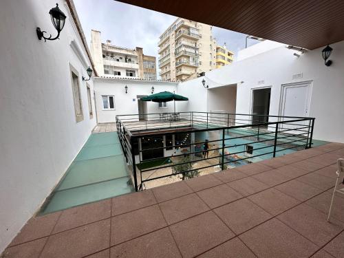 a balcony with a table and a green umbrella at Albergaria Formosa in Faro