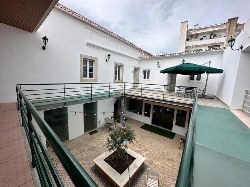 einen Balkon eines weißen Gebäudes mit einem grünen Regenschirm in der Unterkunft Albergaria Formosa in Faro