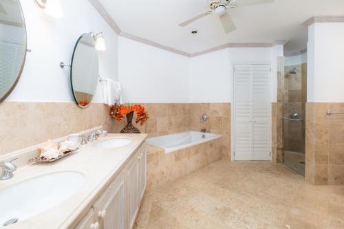 a bathroom with two sinks and a tub and a mirror at Royal Westmoreland - Royal Apartment 214 by Island Villas in Saint James