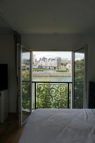 a bedroom with a bed and a view of a city at Résidences Grande Jatte, Face Seine, Suites Luxe 52m2 à 97m2, Hôpital Américain à 600m in Neuilly-sur-Seine