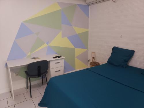 een slaapkamer met een bureau en een bed met een blauwe sprei bij ptit coin hibiscus in Pointe-Noire