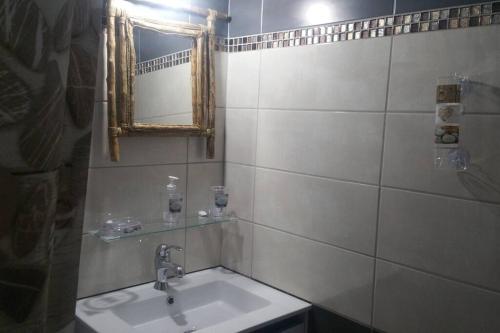 W łazience znajduje się umywalka i lustro. w obiekcie ptit coin hibiscus w mieście Pointe-Noire