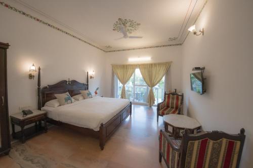 a bedroom with a bed and a chair in it at Ranakpur Safari Resort in Sādri