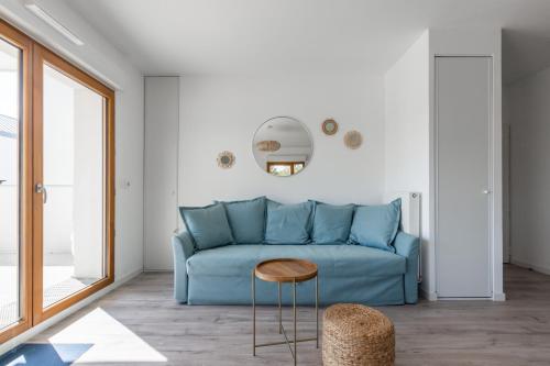 un salon avec un canapé bleu et une table dans l'établissement Chez André By Plaza - Proche Disneyland Paris, à Magny-le-Hongre
