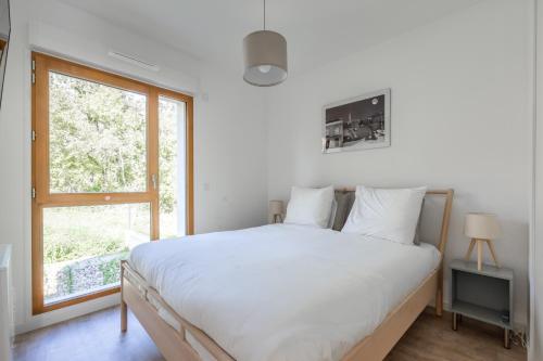 une chambre avec un lit blanc et une fenêtre dans l'établissement Chez André By Plaza - Proche Disneyland Paris, à Magny-le-Hongre
