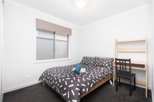 a bedroom with a bed and a chair and a window at 3bedroom Modern Home in Mt Barker, 8km to Hahndorf in Mount Barker