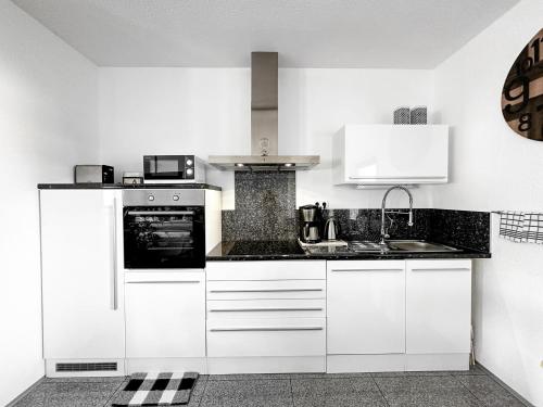 eine Küche mit weißen Schränken und einer Spüle in der Unterkunft Ebony & Ivory Ferienwohnung in Steinhude