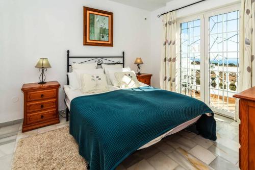 a bedroom with a bed with a green blanket at Casa Los Olivos in Nerja