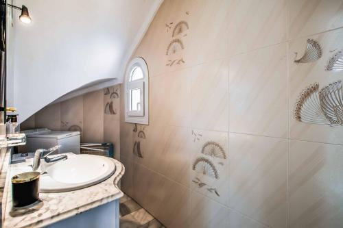 un baño con lavabo y una pared con dibujos. en Casa Los Olivos en Nerja