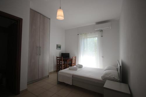 a white bedroom with a bed and a window at Mato Rooms in Himare