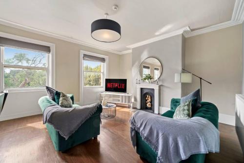 a living room with two green chairs and a fireplace at Exquisite Georgian Apartment with Reserved Parking in Wakefield