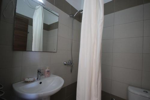 a bathroom with a sink and a shower curtain at Mato Rooms in Himare