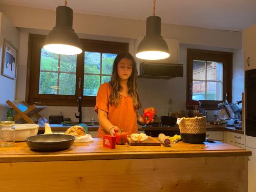 a woman standing at a kitchen counter preparing food at Wonderful apartment overlooking the Swiss alps in Chateau-d'Oex