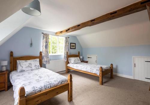 a bedroom with two beds and a window at Locks Lane Cottage in Geldeston