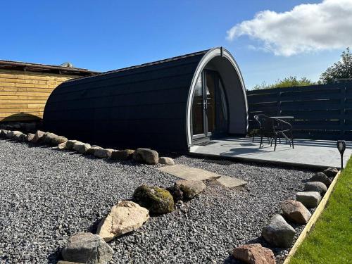 a black and white house with a patio and rocks at Lochside Lodge Pod in Lairg