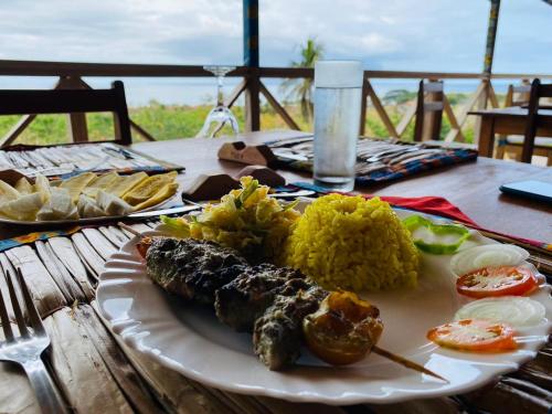 a plate of food with rice and vegetables on a table at Monte Mar SãoTomé in M. Peixe