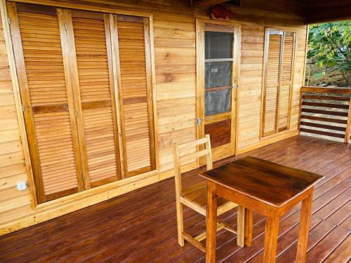 a wooden porch with a table and chairs on a deck at Monte Mar SãoTomé in M. Peixe