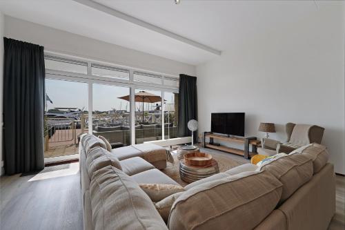 a living room with a large couch and a television at Kabbelaarsbank 503 - Port Marina Zélande in Ouddorp
