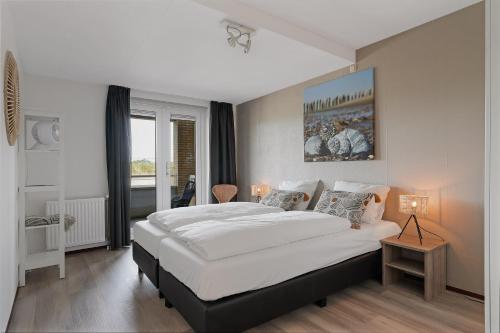 Un dormitorio con una gran cama blanca y una ventana en Appartement in Zeeland - Kabbelaarsbank 503 - Port Marina Zélande - Ouddorp - not for companies, en Ouddorp