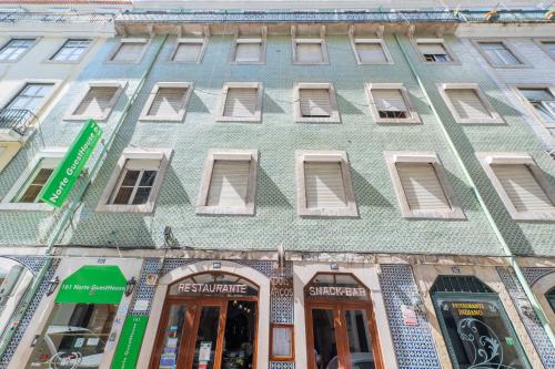 a green building with windows on a city street at Norte Guest House in Lisbon