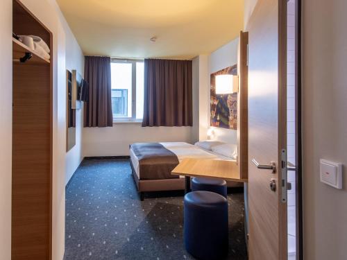 um quarto de hotel com uma cama e uma secretária em B&B Hotel Bayreuth em Bayreuth