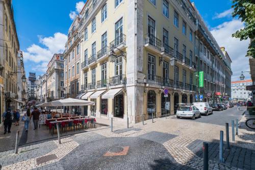 ulica miejska z budynkami, stołami i samochodami w obiekcie Norte Guest House w Lizbonie