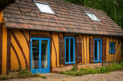 una casa con ventanas azules y techo en Gîte de l'Ecrin de l'Andelle - Forêt de Lyons, 