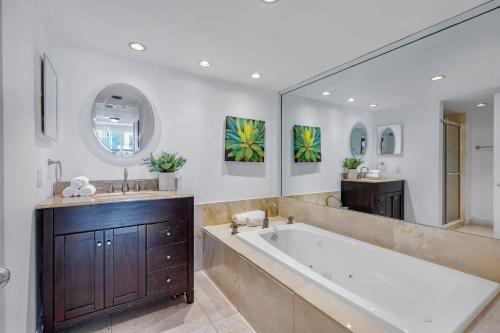uma casa de banho com uma banheira grande e um espelho grande em Bayfront Gem with Balcony and Pool em Miami