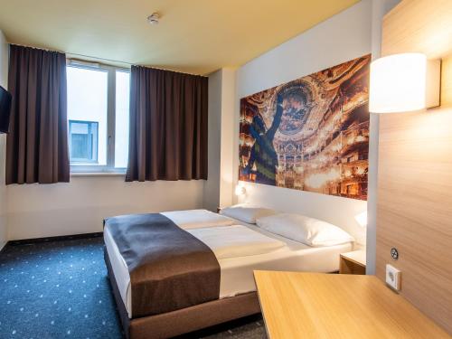 une chambre d'hôtel avec un lit et un tableau sur le mur dans l'établissement B&B Hotel Bayreuth, à Bayreuth