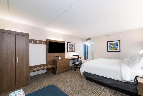 a large hotel room with a bed and a tv at Holiday Inn Express Naperville, an IHG Hotel in Naperville
