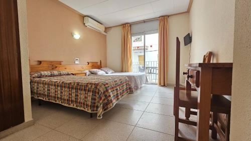 a hotel room with two beds and a balcony at Hostal Los Maños in Blanes