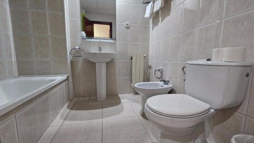 La salle de bains blanche est pourvue de toilettes et d'un lavabo. dans l'établissement Hostal Los Maños, à Blanes