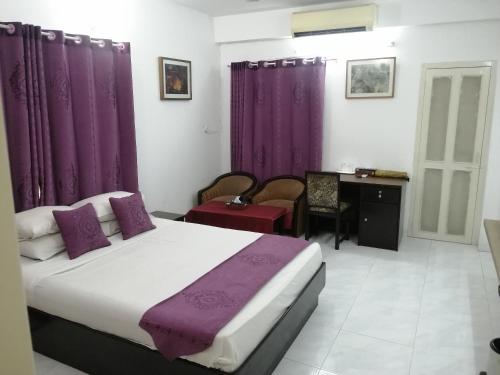 1 dormitorio con cama con cortinas moradas y escritorio en Bay Marina Cox's Bazar, en Kelātali