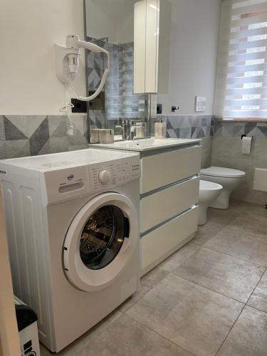 uma máquina de lavar roupa branca na casa de banho com WC em HappyHome Bilocale centro storico Rivarolo Canavese em Rivarolo Canavese