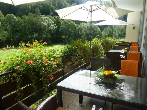 een patio met een tafel, een parasol en bloemen bij Landhotel Lodge by Landhotel Krolik in Daun