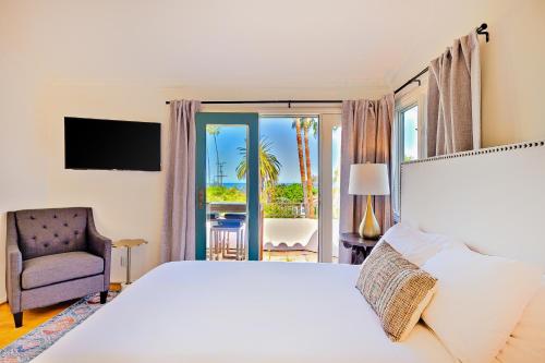 - une chambre avec un grand lit blanc et une chaise dans l'établissement La Jolla Cove Beauty, à San Diego