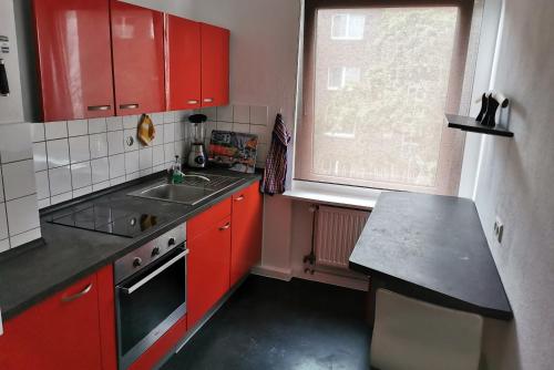 eine Küche mit roten Schränken, einem Waschbecken und einem Fenster in der Unterkunft Private Apartment in Hannover