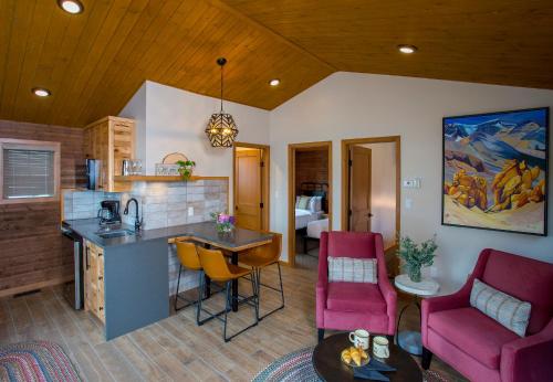 a kitchen and living room with pink chairs and a table at Bear Hill Lodge in Jasper
