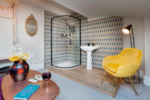 a bathroom with a shower and a yellow chair and a table at Albert Road Apartments Flat 2 in Colne