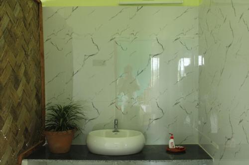 bagno con lavandino e parete in marmo di Kumirmari Ecotourism a Japur