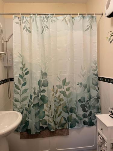 a bathroom with a shower curtain with plants on it at A Room in Central Park Apts in Carrick on Shannon