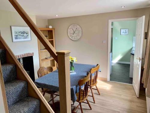 a dining room with a table and chairs and a clock at Shipmeadow Cosy Cottage in Beccles