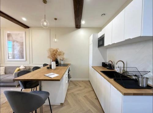 a kitchen with white cabinets and a table and chairs at Le Lamartine - vue Saône - Baignoire îlot in Mâcon