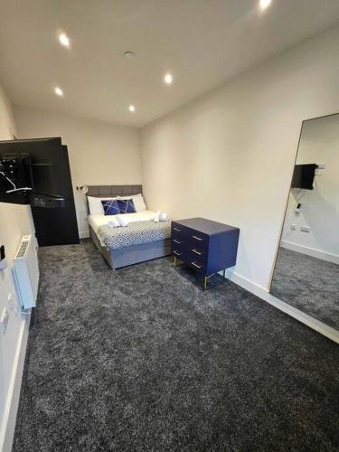 a bedroom with a bed and a dresser and a mirror at Stunning City Center Prime Location Flat - TV in every bedroom in Neath