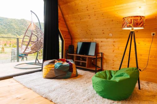 a living room with a television and a lamp at Oda Riverside Cottages in Aragvispiri