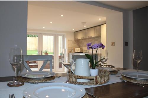 a dining room with a table with plates and wine glasses at Idyllic period cottage, Ramsbury, Nr Marlborough in Ramsbury