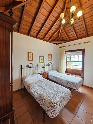 a bedroom with three beds and a wooden ceiling at Corral de Payo Casita Blanca in Breña Baja