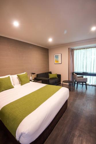 a hotel room with a large bed and a living room at The Waverley International Hotel in Glen Waverley